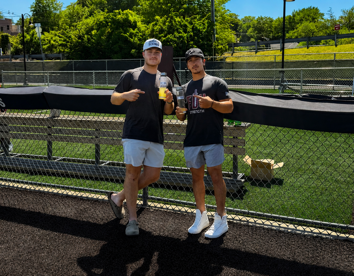 HYPR founders TJ Werner and Caleb Walker holding HYPR bottles at a baseball field